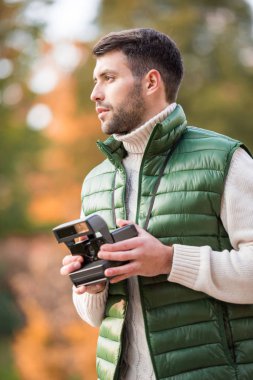 Yakışıklı adam holding anlık fotoğraf makinesi