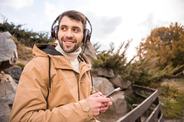 Man in headphones holding smartphone — Stock Photo, Image