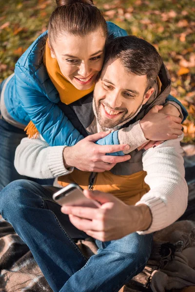 Beau couple souriant regardant smartphone — Photo