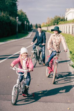 Cheerful family biking in park 