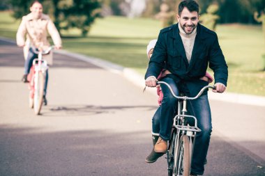 Happy family riding bicycles in park clipart