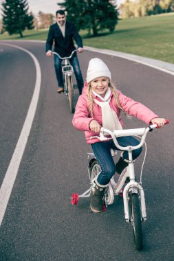 Gülümseyen kız babasıyla Bisiklete binme