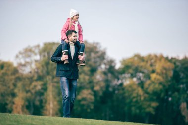 Smiling father carrying daughter on shoulders