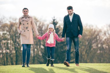 Mutlu bir aile parkta yürüyor.