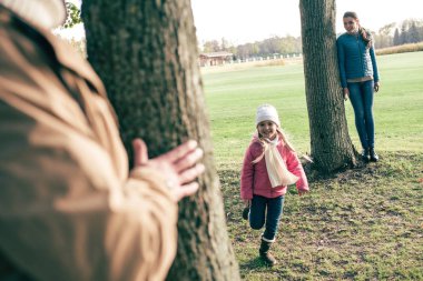 Parents playing hide-and-seek with daughter clipart