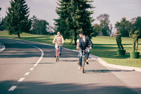 Happy family riding bicycles in park — Stock Photo, Image