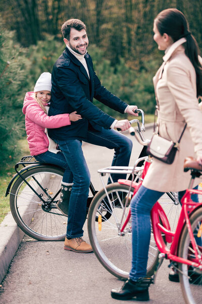 Cheerful family standing with bicycles 