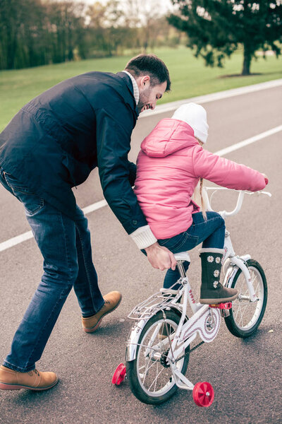 Father teaching daughter to ride bicycle