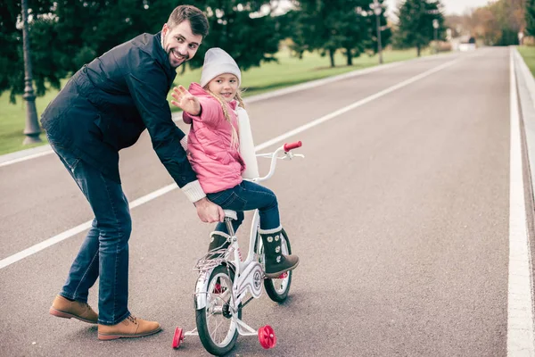 Отец учит дочь кататься на велосипеде — стоковое фото