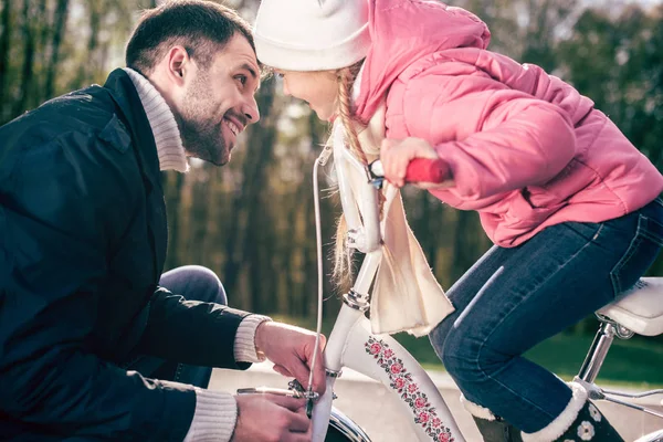 Padre chequeando bicicleta de hija pequeña — Foto de Stock