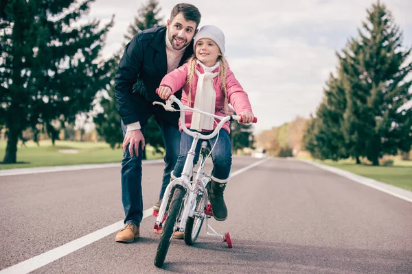 Ojciec uczy córkę jeździć na rowerze. — Zdjęcie stockowe