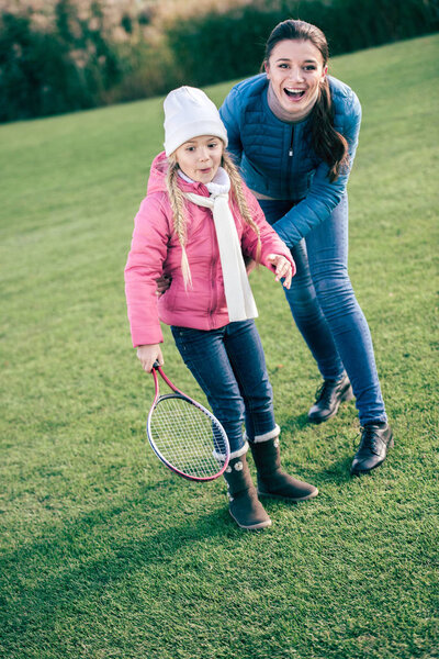 Smiling mother with daughter playing badminton