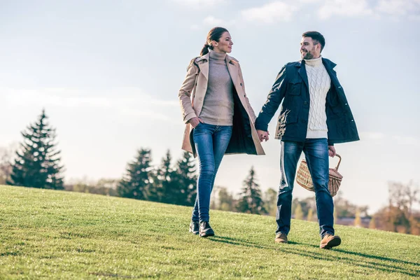 Pareja feliz caminando con cesta de picnic — Foto de Stock