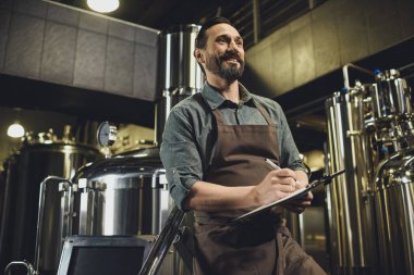 Worker inspecting equipment at brewery clipart