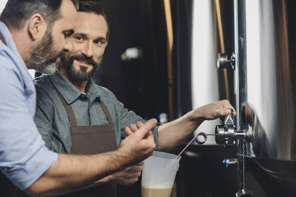 Brewery workers pouring beer — Stock Photo, Image