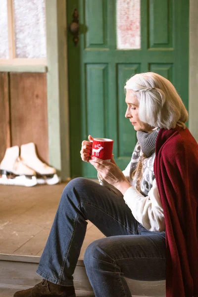 Frau hält Becher mit Heißgetränk in der Hand — kostenloses Stockfoto