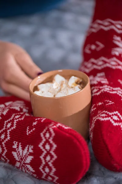 Female feet and cup with hot chocolate