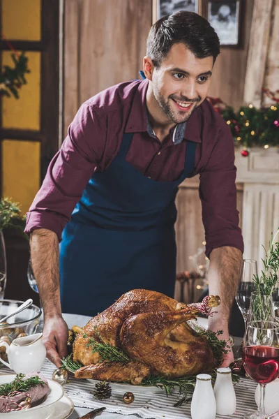 Man putting turkey on festive table — Stock Photo, Image