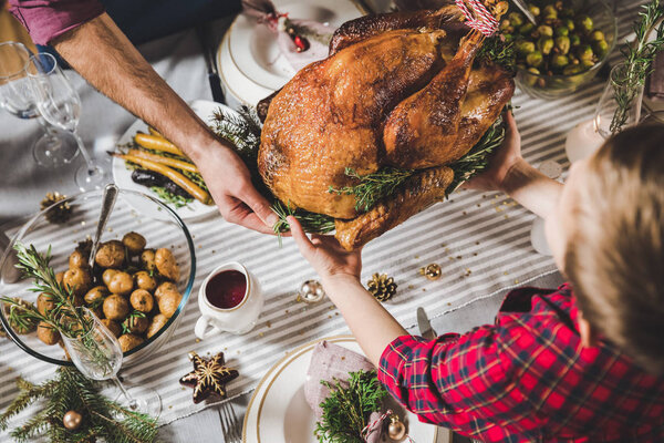 Father and son holding roasted turkey 