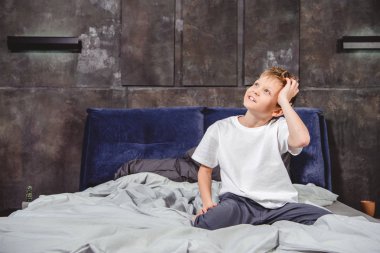 Thoughtful boy sitting on bed  clipart