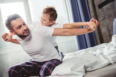Happy father and son on bed  clipart