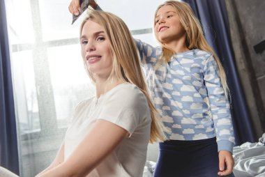 Daughter combing hair of mother clipart
