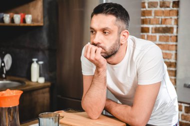 Thoughtful man in kitchen clipart