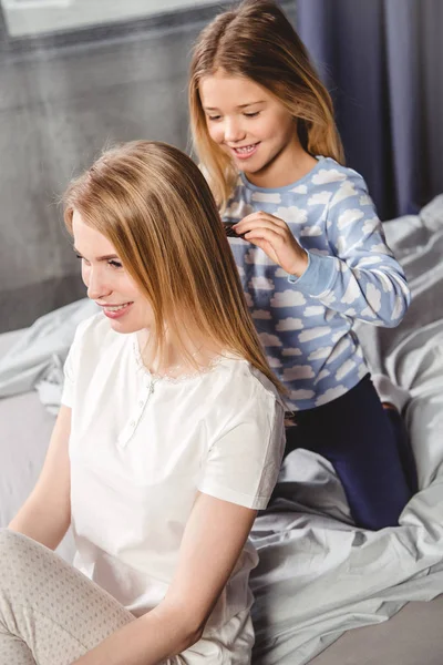 Дочь расчесывает волосы матери — стоковое фото