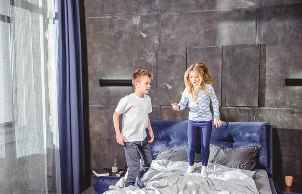 Siblings jumping on bed — Stock Photo, Image