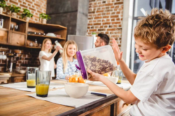 Junge schüttet Kornflockenringe — Stockfoto