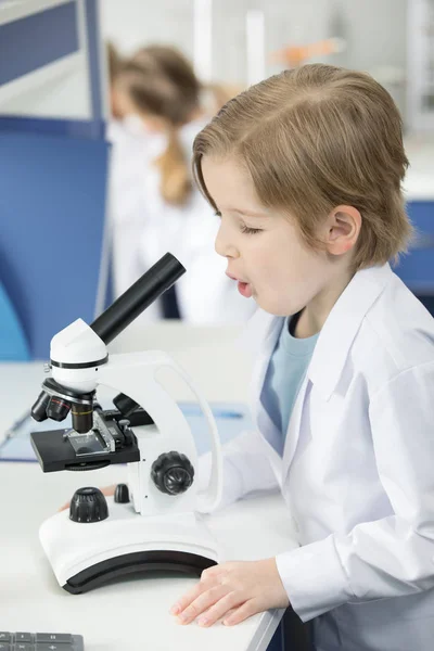 Colegial usando microscopio — Foto de stock gratuita