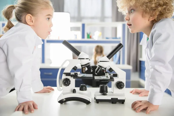 Schoolchildren using microscopes — Stock Photo, Image