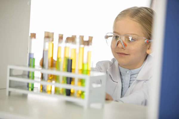 Schoolgirl looking at test tubes — Stock Photo, Image