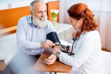 Doctor measuring pressure of patient clipart