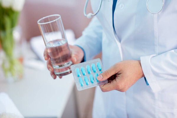 доктор держит таблетки и воду
