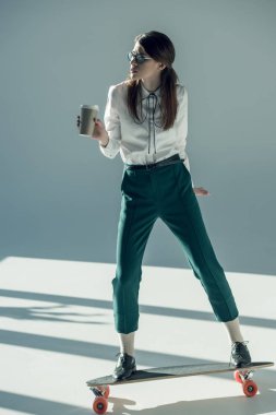 hipster woman standing on skateboard