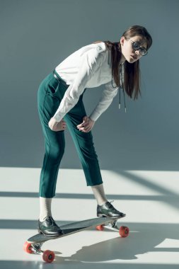 hipster woman standing on skateboard