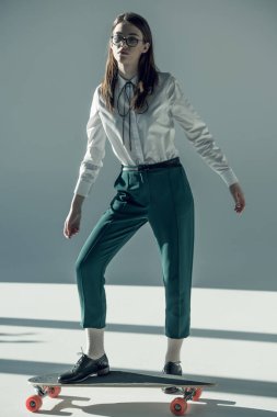 hipster woman standing on skateboard
