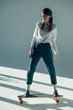 hipster woman standing on skateboard