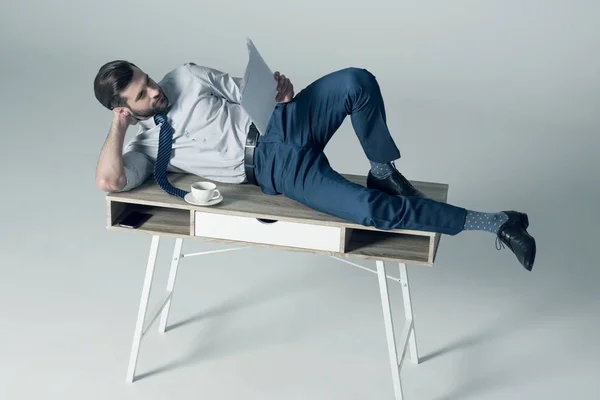 Бизнесмен, лежащий на столе — стоковое фото