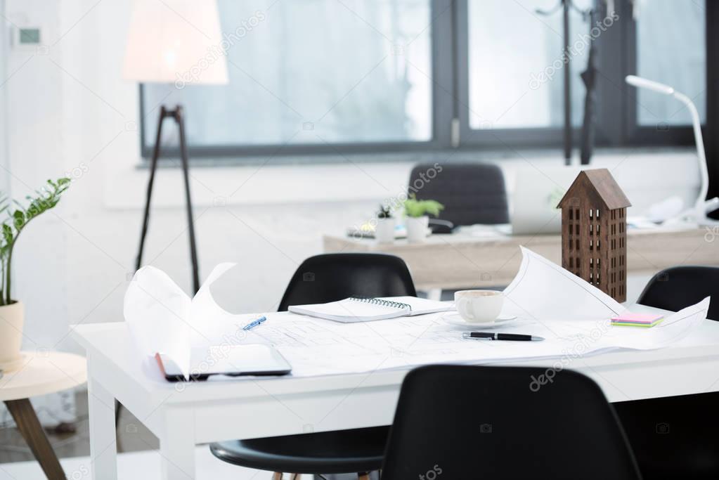 Modern office workplace with blueprints and papers on desk