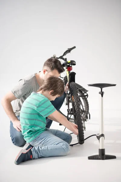 Padre e hijo inflando neumático de bicicleta — Foto de Stock