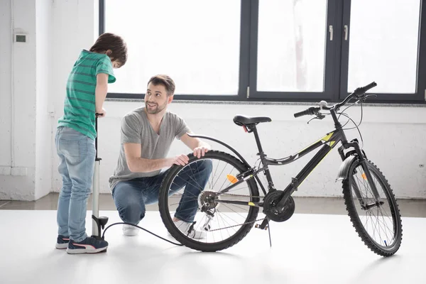 Father and son inflating bicycle tire — Stock Photo, Image