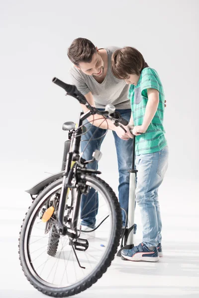 Отец и сын надувают велосипедную шину — стоковое фото