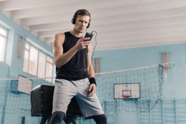 Sportsman in headphones with smartphone clipart