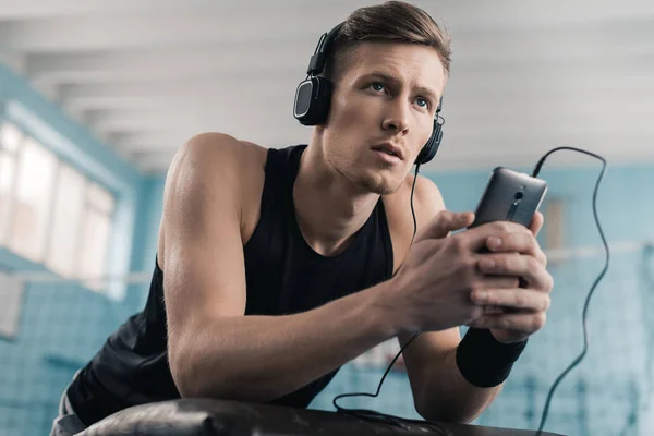 Αθλητικός τύπος στα ακουστικά με έξυπνο κινητό τηλέφωνο — Φωτογραφία Αρχείου