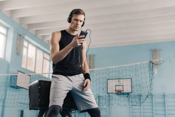 Sportsman in headphones with smartphone — Stock Photo, Image