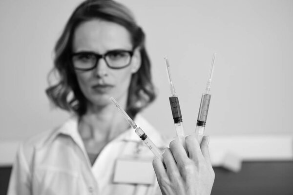 Доктор держит шприцы.
