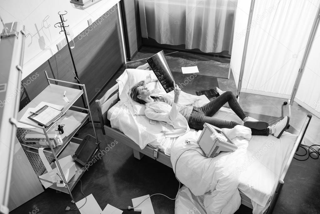 High angle view of doctor examining x-ray picture on bed, black and white photo