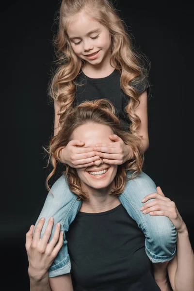 Daughter sitting on mother's shoulders — Stock Photo, Image